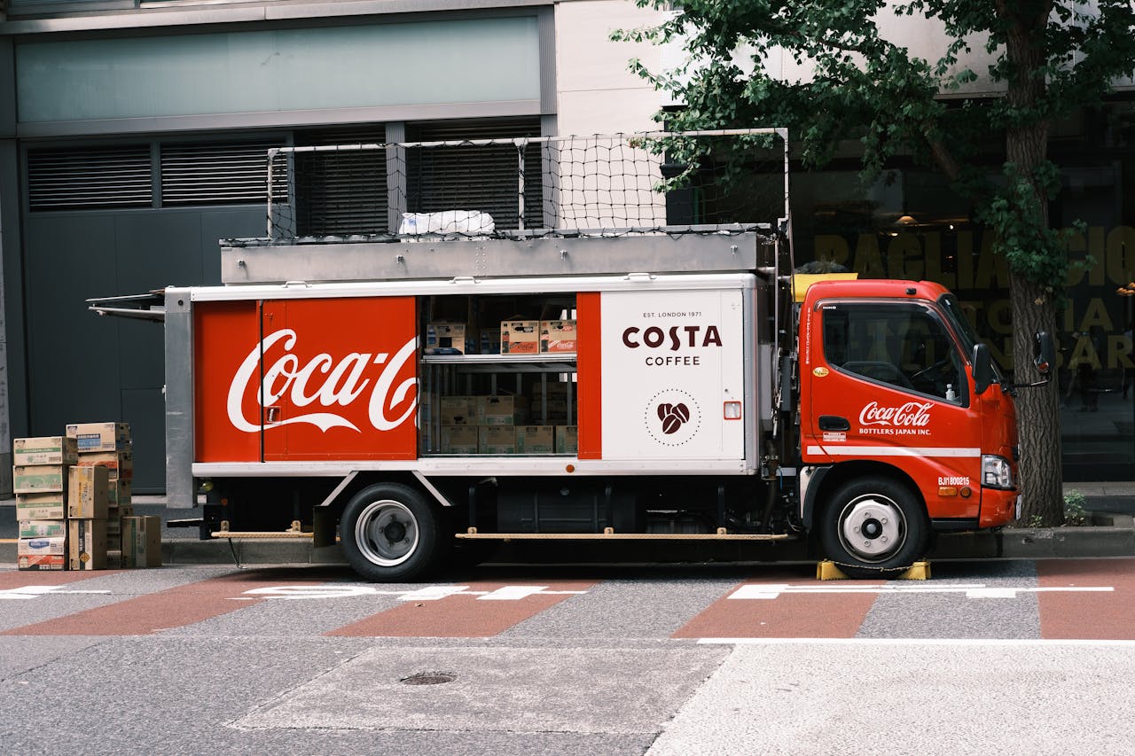 Coca-Cola delivery truck parked on a city street next to a building.